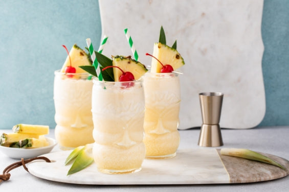 Three non-alcoholic pina coladas with cherries and pineapple.